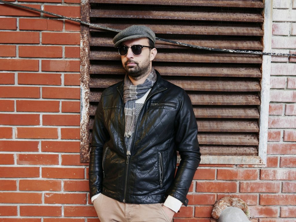 Portrait of handsome young man in leather jacket. Brick wall, sunglasses, leather jacket.